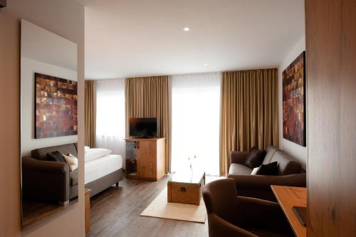 uma sala de estar com um sofá, uma cama e uma televisão em Hotel Schwaiger em Glonn