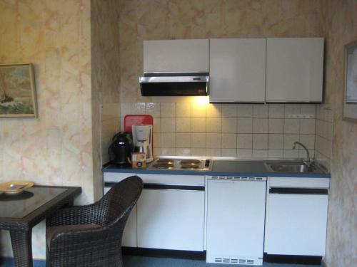a kitchen with white cabinets and a sink and a table at Haus Kuhlmann in Büsum