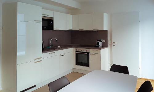 a kitchen with white cabinets and a table and chairs at 4 Beds and More Vienna Apartments - Contactless check-in in Vienna