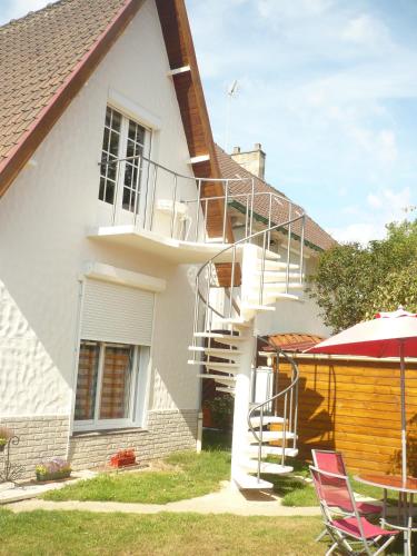 ein weißes Haus mit einer Treppe, einem Tisch und Stühlen in der Unterkunft Chez Nicole in Marconne