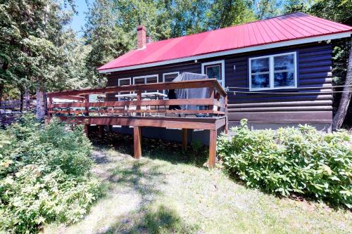 a log cabin with a red roof and a wooden deck at Pebble Cove in The Highlands