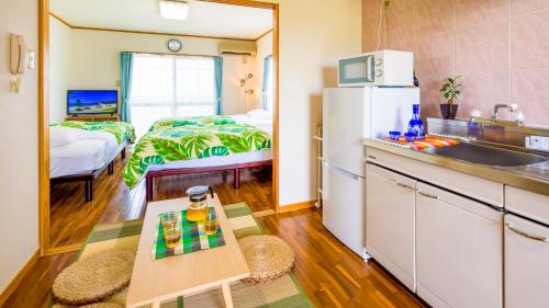 a kitchen with a refrigerator and a bed in a room at Hotel Sunset ZANPA in Yomitan