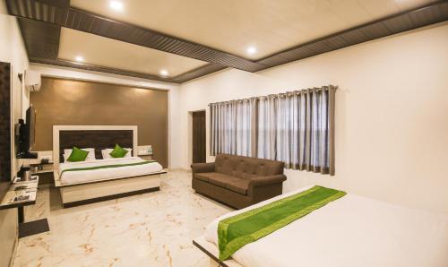 a bedroom with a bed and a couch and a chair at Yashogopal Resortico in Vrindāvan