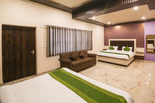 a hotel room with two beds and a couch at Yashogopal Resortico in Vrindāvan