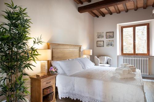um quarto com uma cama branca e uma planta em La Casetta di Brunello em Montalcino