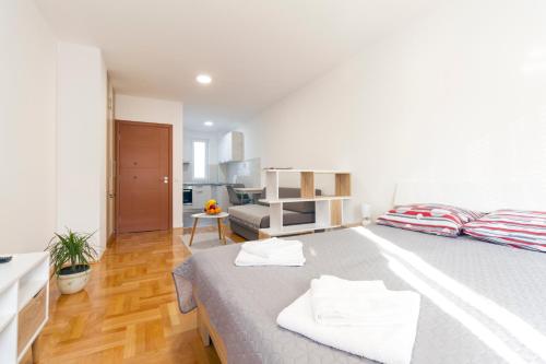a white bedroom with a large bed with two towels at Tea Studio Apartments in Niš