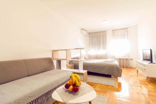 a living room with a couch and fruit on a table at Tea Studio Apartments in Niš