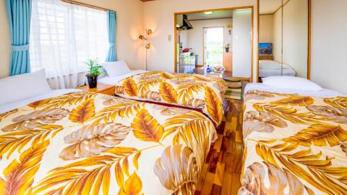 1 dormitorio con 2 camas con hojas impresas en Hotel Sunset ZANPA, en Yomitan