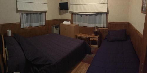 a hotel room with two beds and a tv at Hostal Chalet Las Violetas in Punta Arenas