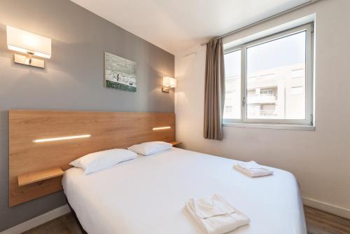 a bedroom with a large white bed and a window at Residhotel Le Grand Prado in Marseille