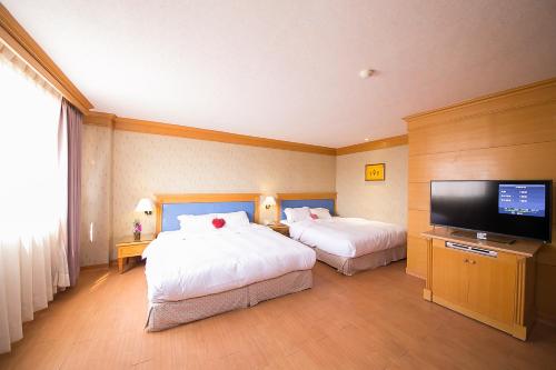 a hotel room with two beds and a flat screen tv at European Castle歐堡商務汽車旅館有限公司 in Xinying