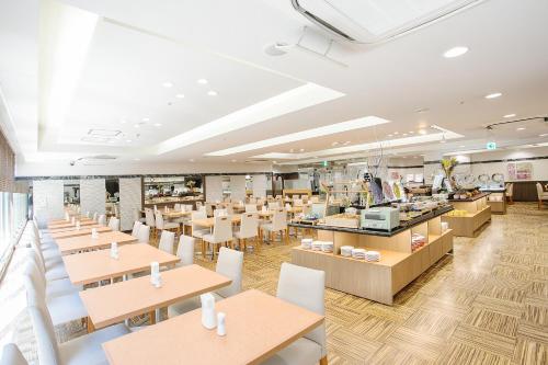 a restaurant with wooden tables and white chairs at Hotel Hokke Club Fukuoka in Fukuoka