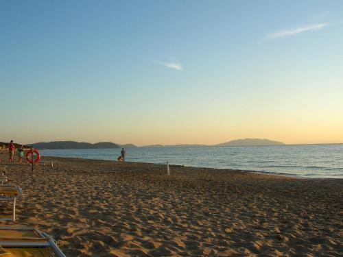 a person walking on the beach at sunset at La Coccinella Residence in San Vincenzo