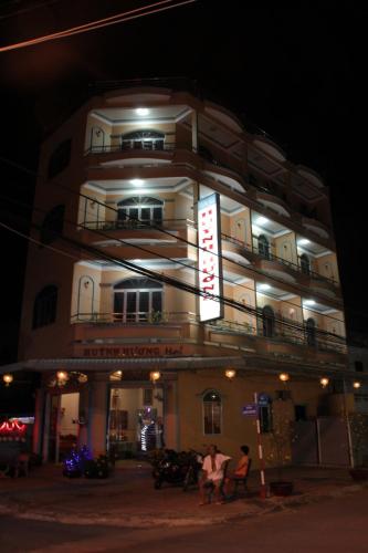 a building with people sitting in front of it at night at Huỳnh Hương Guesthouse in Ha Tien