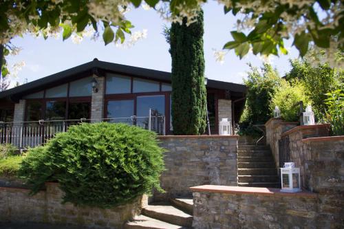 a house with a stone wall and a tree at Agriturismo Poderi Zunino in Ponti