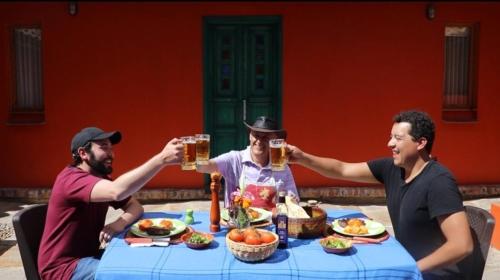 three men sitting around a table drinking beer at La Estancia de la Pradera Cabana Fiba in Nobsa