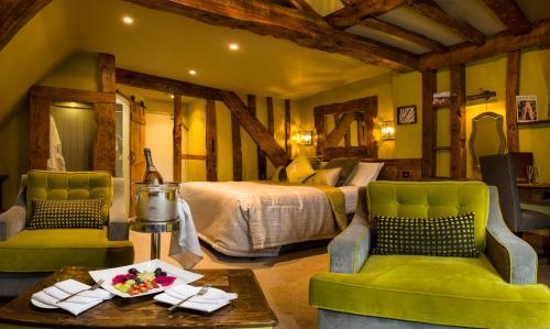 a bedroom with a bed and two chairs and a table at Hatherley Manor Hotel & Spa in Gloucester