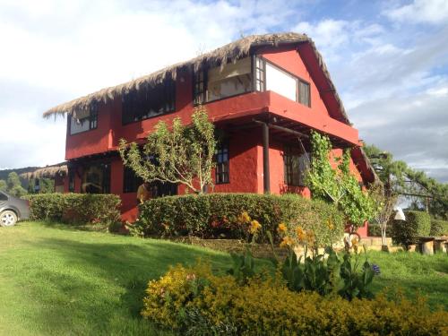 a red building with a grass roof at La Estancia de la Pradera Cabana Fiba in Nobsa