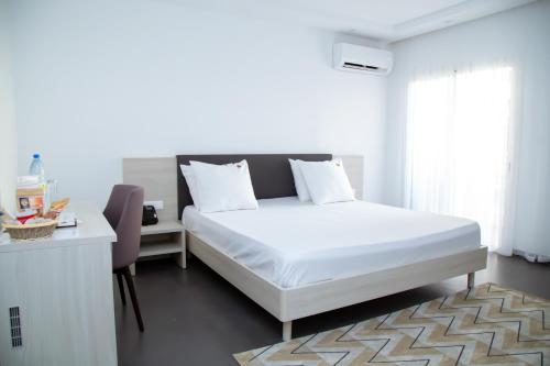 a bedroom with a bed and a desk and a window at Le Ndiambour Hôtel et Résidence in Dakar