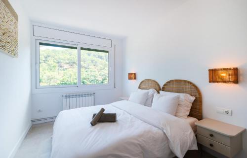 Un dormitorio blanco con una cama con una cruz. en Gala Mar - Sa Riera / Begur Sea View, en Begur