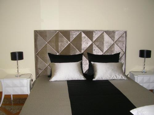 um quarto com uma cama grande e almofadas pretas e brancas em Villa d'Arcos em Arcos