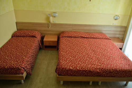 a room with two beds and a table at Hotel Sorriso in Toscolano Maderno