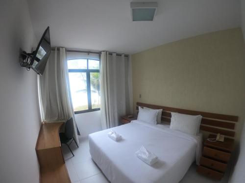 sypialnia z białym łóżkiem i oknem w obiekcie Hotel Bellatrix w mieście Macaé