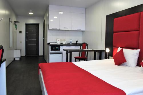 a bedroom with a red bed and a kitchen at City Fox Hotel in Barnaul