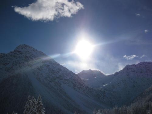 a sun shining on a mountain with snow on it at Hotel Astoria in Arosa