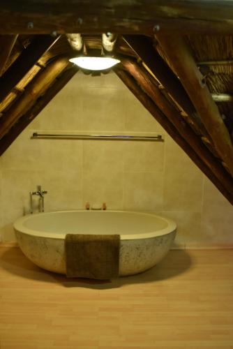 a large stone tub in a bathroom with a ceiling at The Cedars Bed and Breakfast in Centurion
