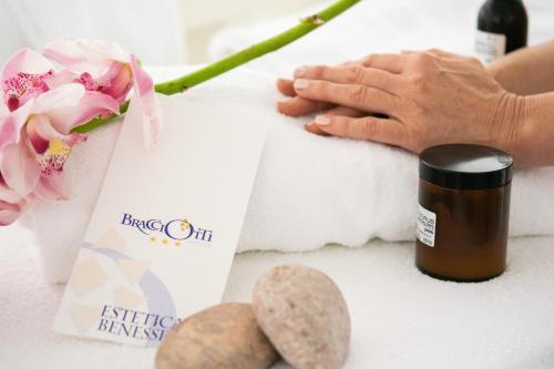 a woman holding a bottle of essential oil next to a flower at Hotel Bracciotti in Lido di Camaiore