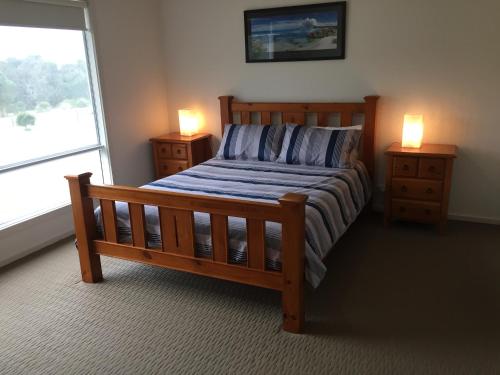 a bedroom with a wooden bed and two night stands at My Island Home in Kingscote