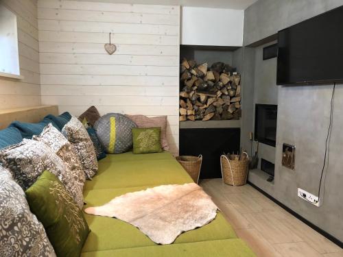 a living room with a green couch and a pile of wood at Chata Magistrála in Bedřichov