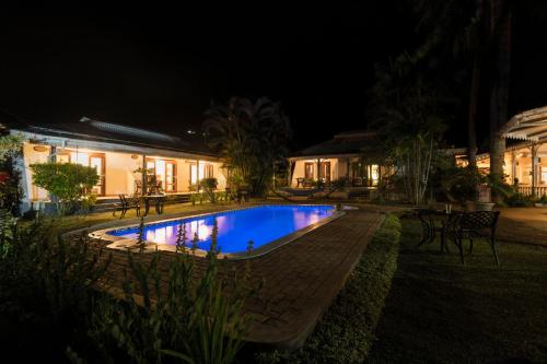 a swimming pool in front of a building at night at Auberge d'Anse Boileau & Restaurant Chez Plume in Anse Boileau