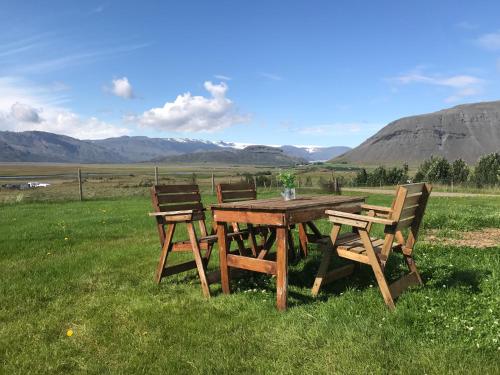 a picnic table and two benches sitting in a field at Setberg Guesthouse in Nesjum