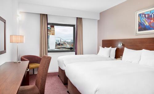 a hotel room with two beds and a desk and a window at Leonardo Hotel Newcastle Quayside in Newcastle upon Tyne