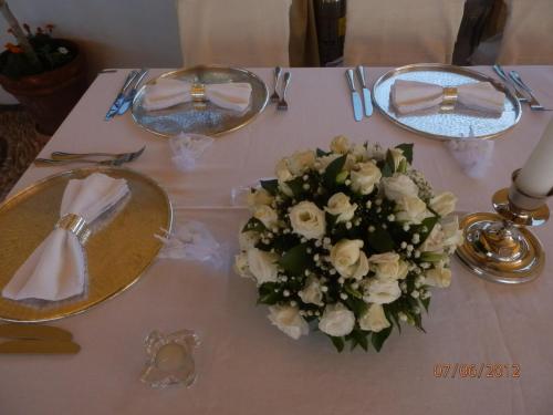 a table with two plates and a bouquet of white flowers at Melenos Art Boutique Hotel in Líndos