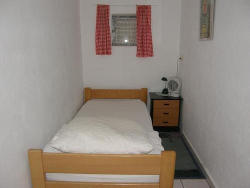 a small bedroom with a bed and a night stand at Appartements & Ferienwohnungen Wolf in Usingen