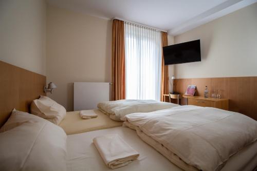 a hotel room with two beds and a flat screen tv at Hotel Goldene Gans in Mannheim