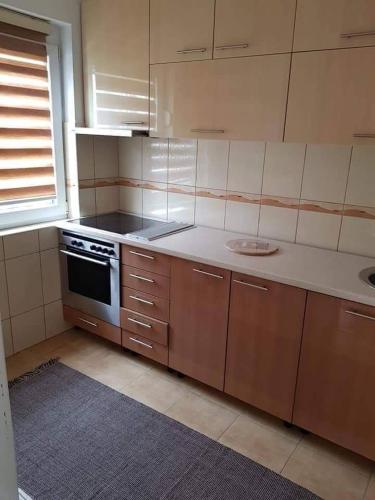 a kitchen with wooden cabinets and a stove top oven at Harmony apartman in Bijeljina