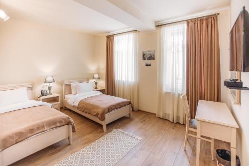 ein Hotelzimmer mit 2 Betten und einem Schreibtisch in der Unterkunft Le Caucase in Tbilisi City