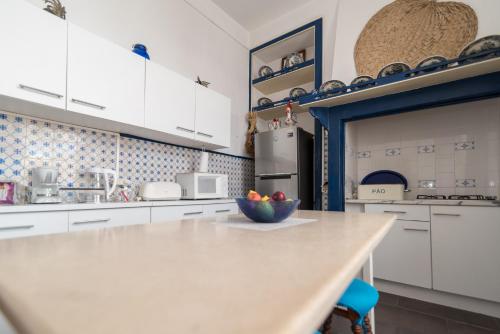 a kitchen with white cabinets and a bowl of fruit on a counter at Chez Odete in Figueira da Foz