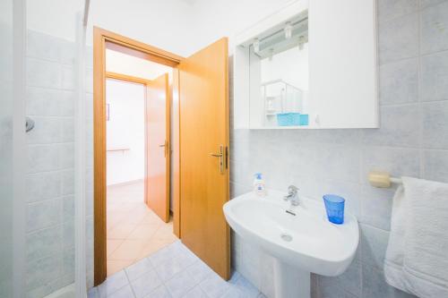 a white bathroom with a sink and a mirror at Mistral Residence in Canneto