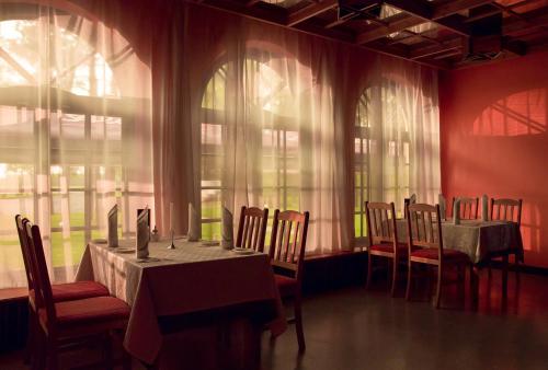 a dining room with tables and chairs and windows at Motel Brencis in Iecava