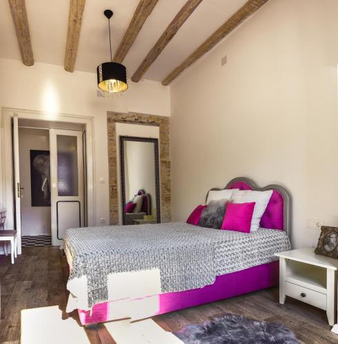 a bedroom with a large bed with pink accents at Emma's rooms B&B in Pula