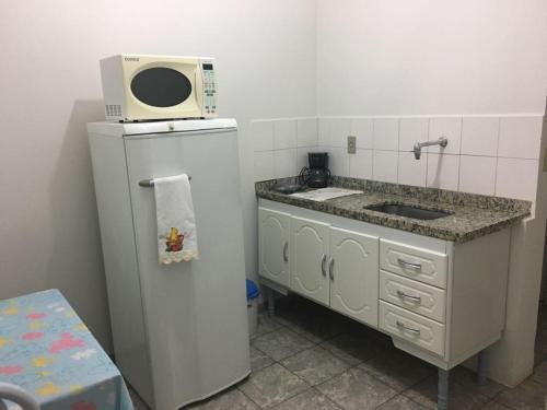 a kitchen with a microwave on top of a refrigerator at Residencias JAC in Paraguaçu Paulista