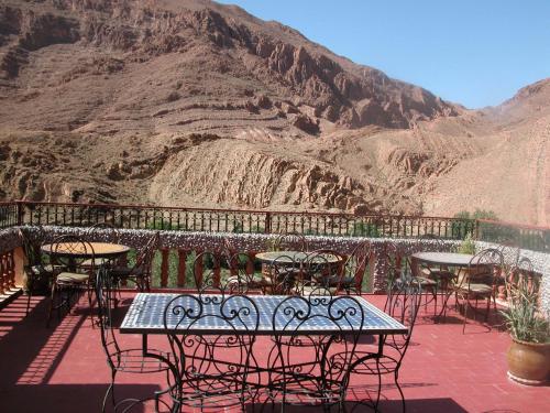 a patio with tables and chairs and a mountain at Maison d'Hôte Valentine in Tinerhir