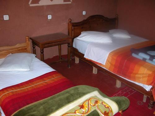 a bedroom with two beds and a table with two tables at Maison d'Hôte Valentine in Tinerhir