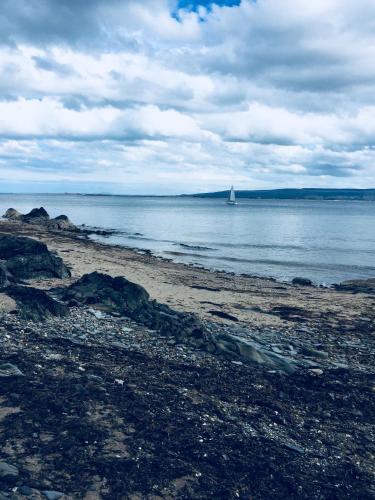 a sail boat in the water with a beach at Foyleview Cottage, Moville in Moville