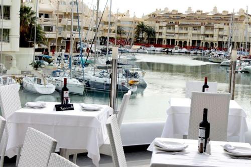 stół z białymi stołami i krzesłami z łodziami w wodzie w obiekcie Apartament Benalmadena Puerto Marina w mieście Benalmádena
